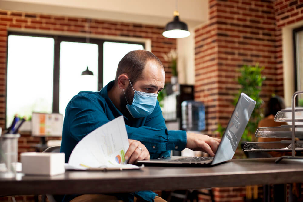Employé en arrêt maladie tenant un ordinateur portable d'entreprise.