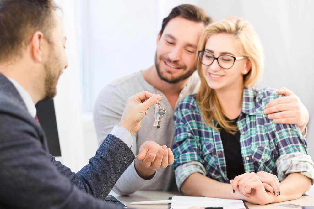 Un couple souriant recevant les clés de leur nouvelle maison après l'obtention de leur financement.