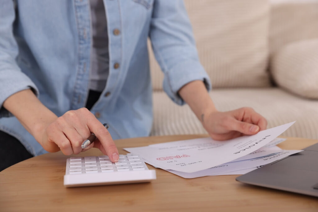 Une personne calculant ses nouvelles mensualités réduites après un regroupement de crédits réussi.