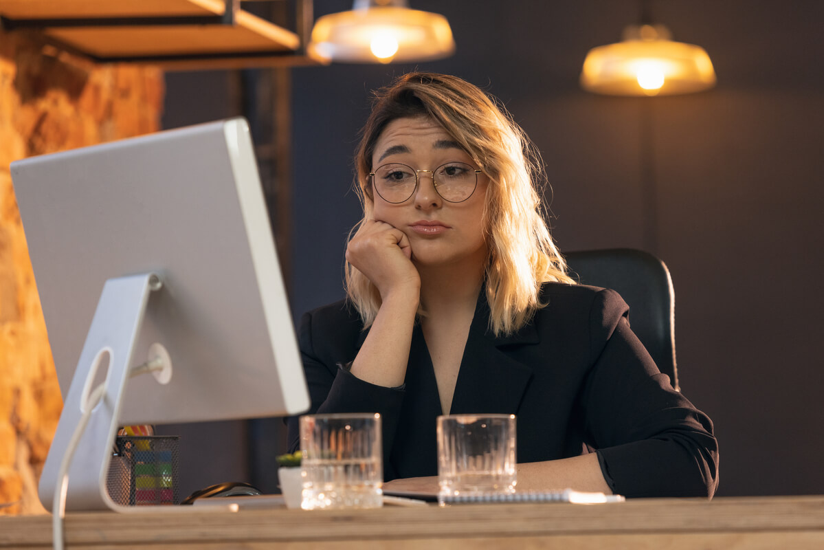 Un employé de bureau assis devant sa table de travail, le regard pensif, exprimant une perte de motivation.