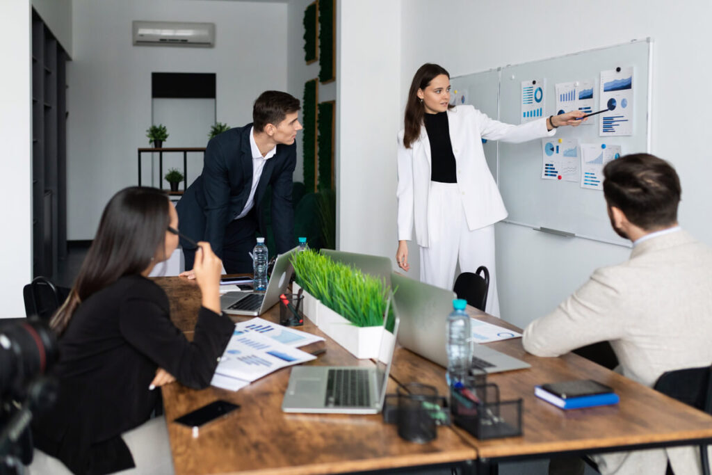 Équipe de travail discutant de la réorganisation des plannings avec un manager autour d'un tableau.