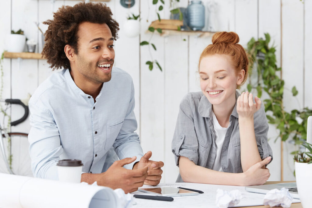 Un couple souriant discutant de ses projets futurs grâce à une meilleure maîtrise de son endettement mensuel.