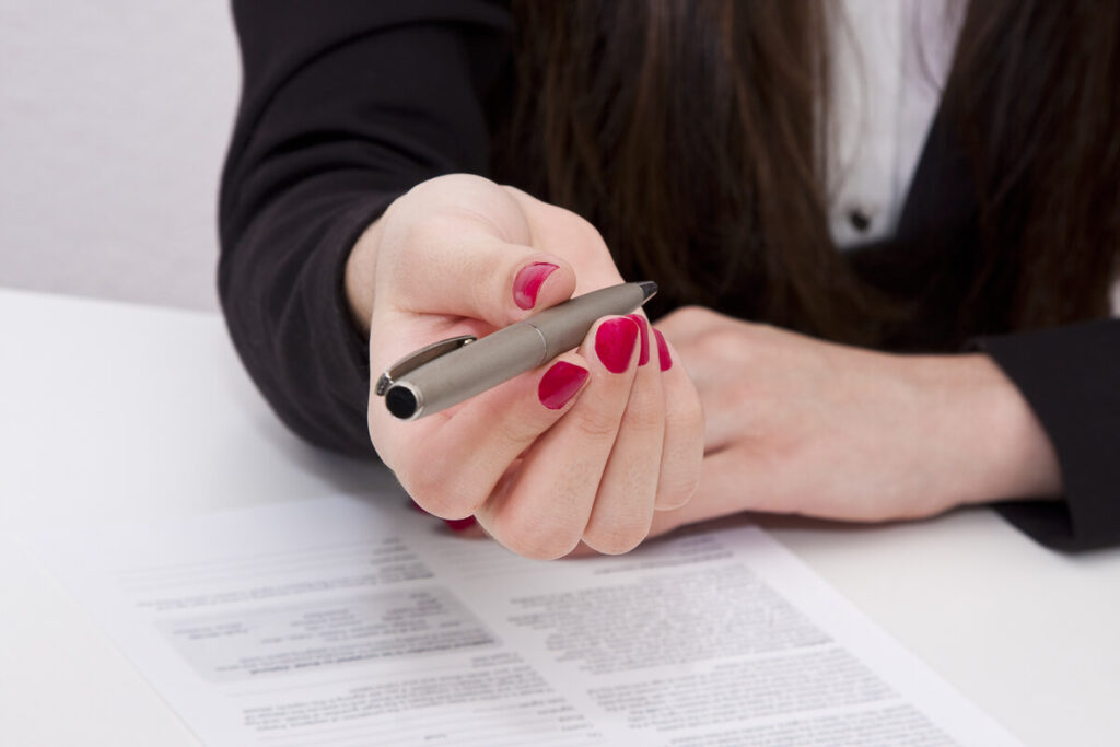 Salarié tenant un stylo au-dessus d'un contrat de travail à durée indéterminée en hésitant à finaliser son engagement