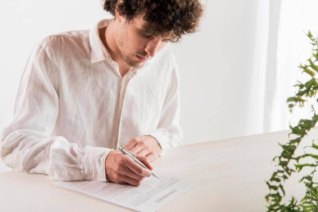 Une personne rédigeant de façon méthodique une attestation officielle de témoignage sur un bureau.