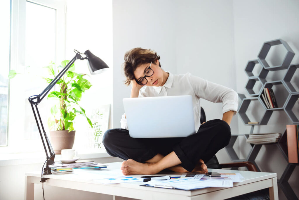 Une personne pensive assise devant son ordinateur de bureau, fatiguée et en manque d'énergie.