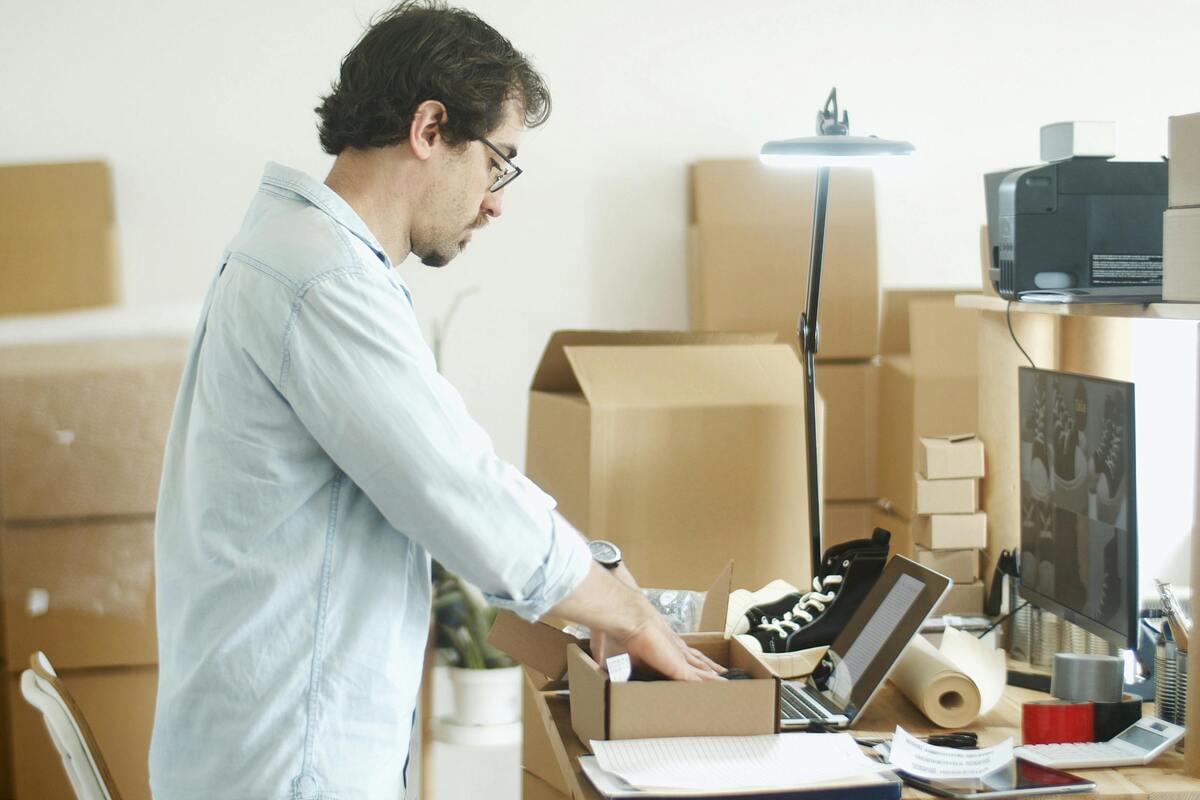 Des cartons de déménagement empilés à côté d'un bureau de travail en entreprise.
