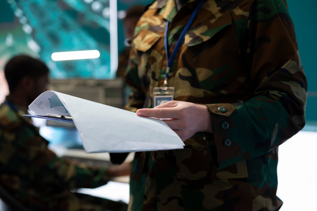 Une personne relisant son relevé de carrière militaire avec une calculatrice posée sur ses dossiers.