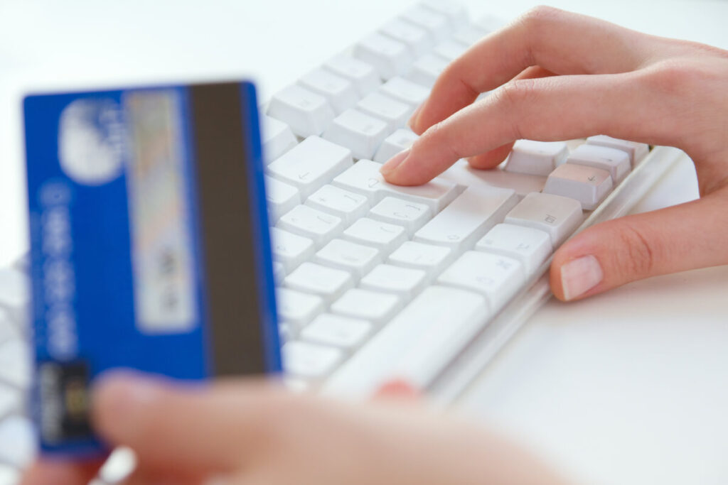 Clé digitale validée mais paiement refusé : pourquoi et que faire 3 Une personne tapant sur un clavier d'ordinateur avec sa carte de paiement posée à côté.