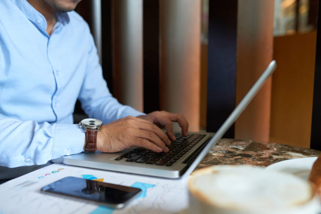 Un chef d'entreprise comparant les offres d'une banque traditionnelle et d'une banque pro en ligne sur son ordinateur.
