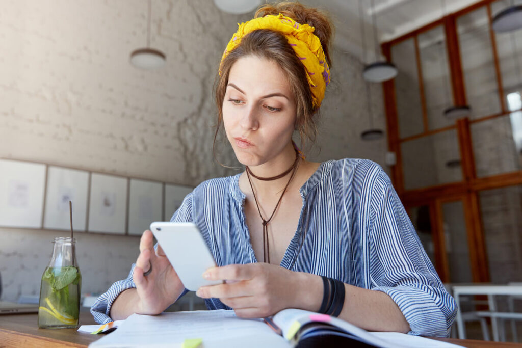 Livret A et RSA : quel impact sur vos droits ? 2 Une personne calculant ses ressources sur son téléphone avec un livret d'épargne ouvert.