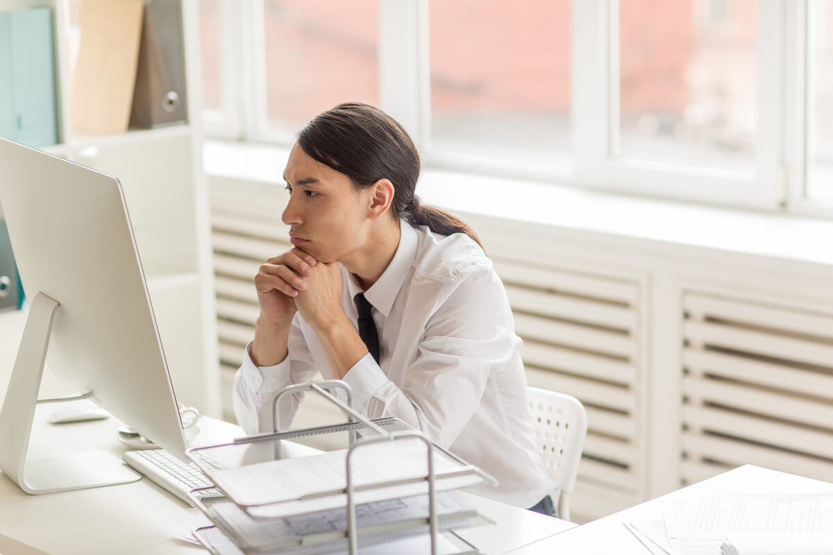 Une personne pensive devant son écran d'ordinateur en consultant son espace personnel administratif.