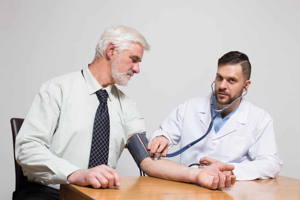 Un médecin prenant la tension d'un patient d'un certain âge lors d'un contrôle de santé.