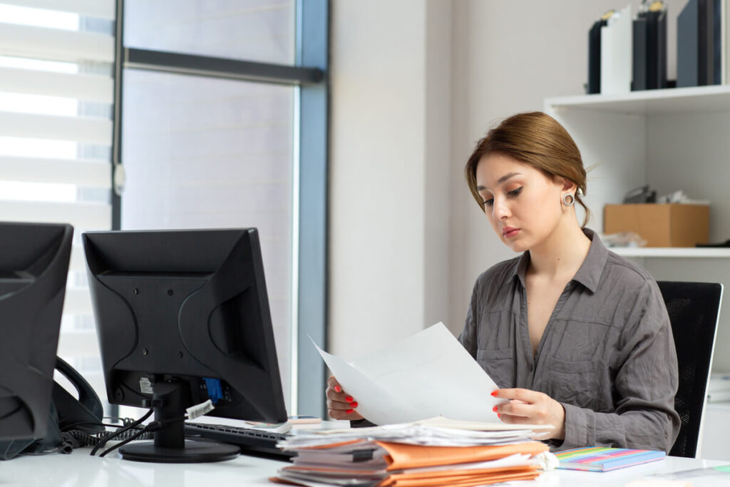 Comment France Travail sait-il que je suis à l'étranger ? Les outils de contrôle 1 Un agent administratif analysant un dossier de demandeur d'emploi derrière son écran de bureau.