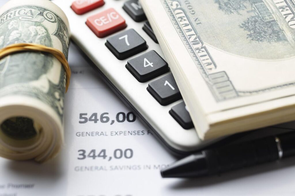 Des billets de banque en dollars américains et en euros posés à côté d'une calculatrice de taux de change.