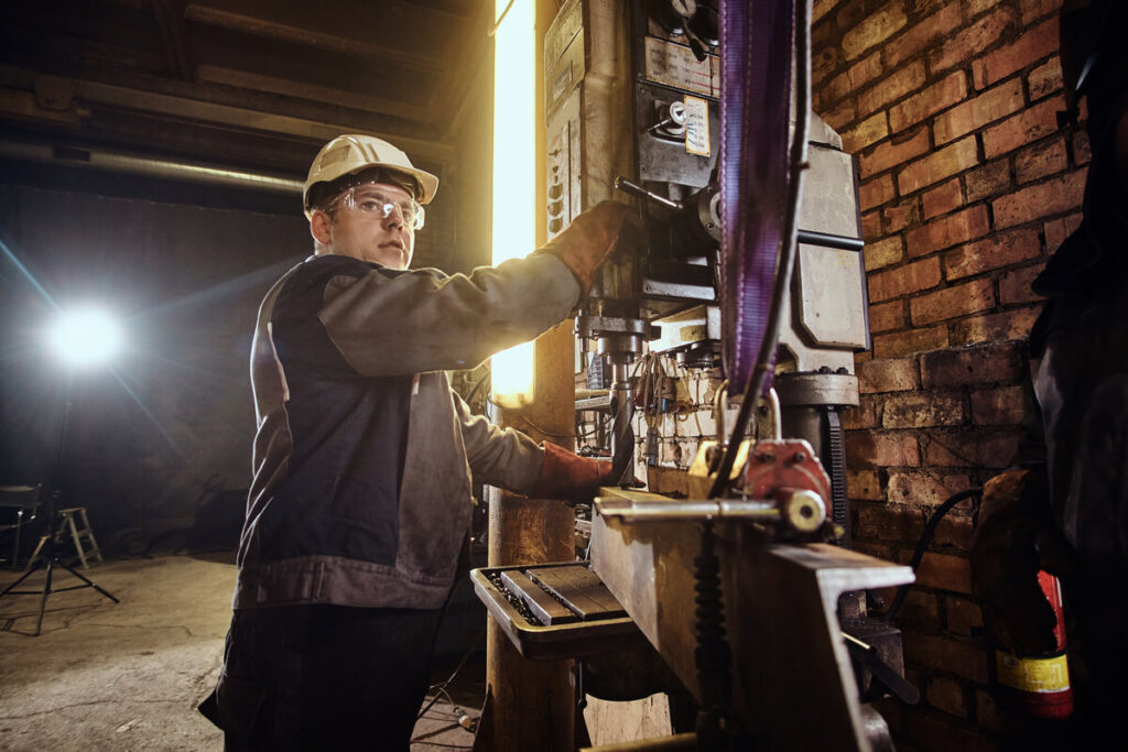 Un ouvrier travaillant de nuit dans une usine automatisée, affichant des signes de fatigue sous la lumière artificielle.