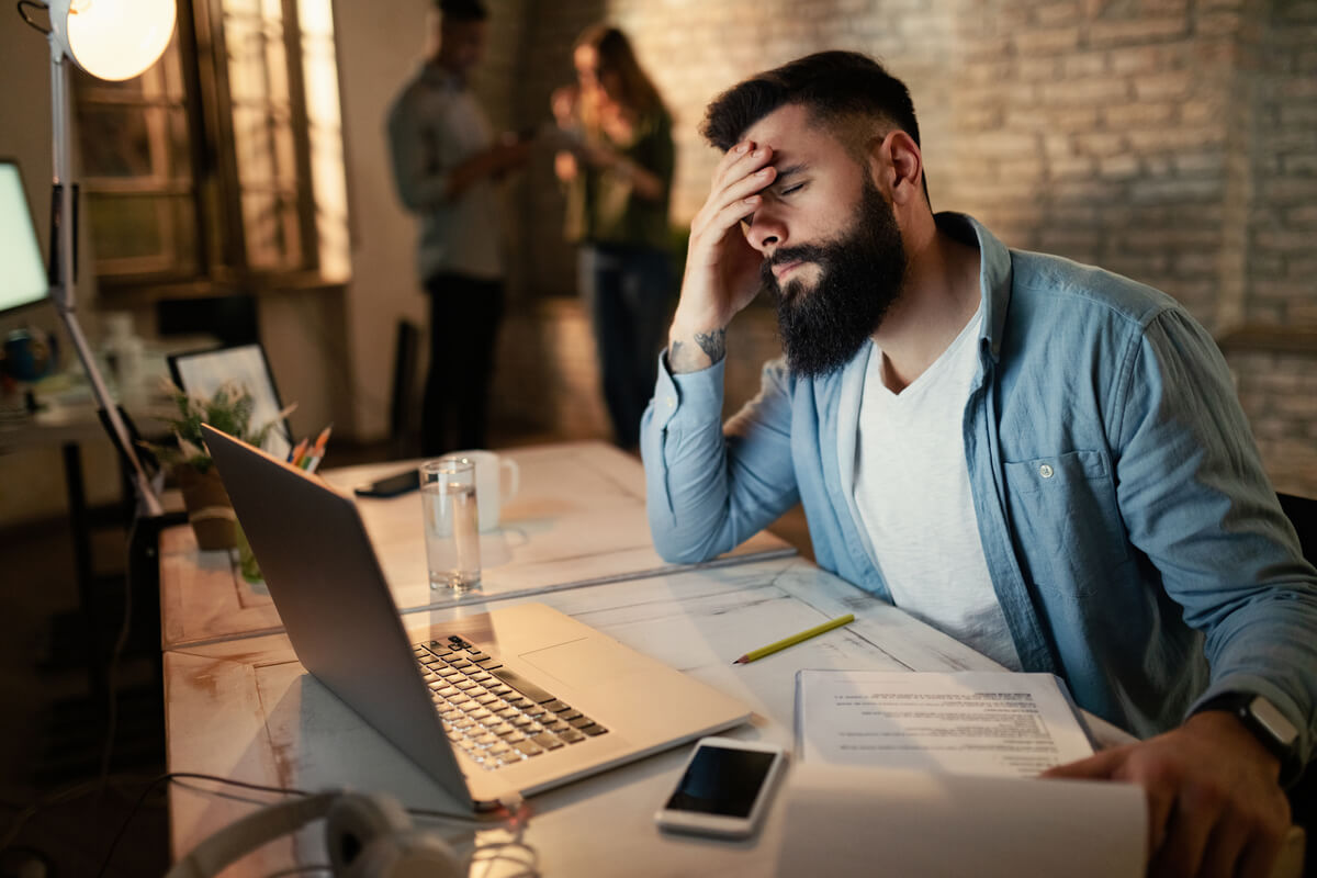 Un employé assis à son bureau qui semble stressé et baisse les yeux lors d'une discussion tendue.