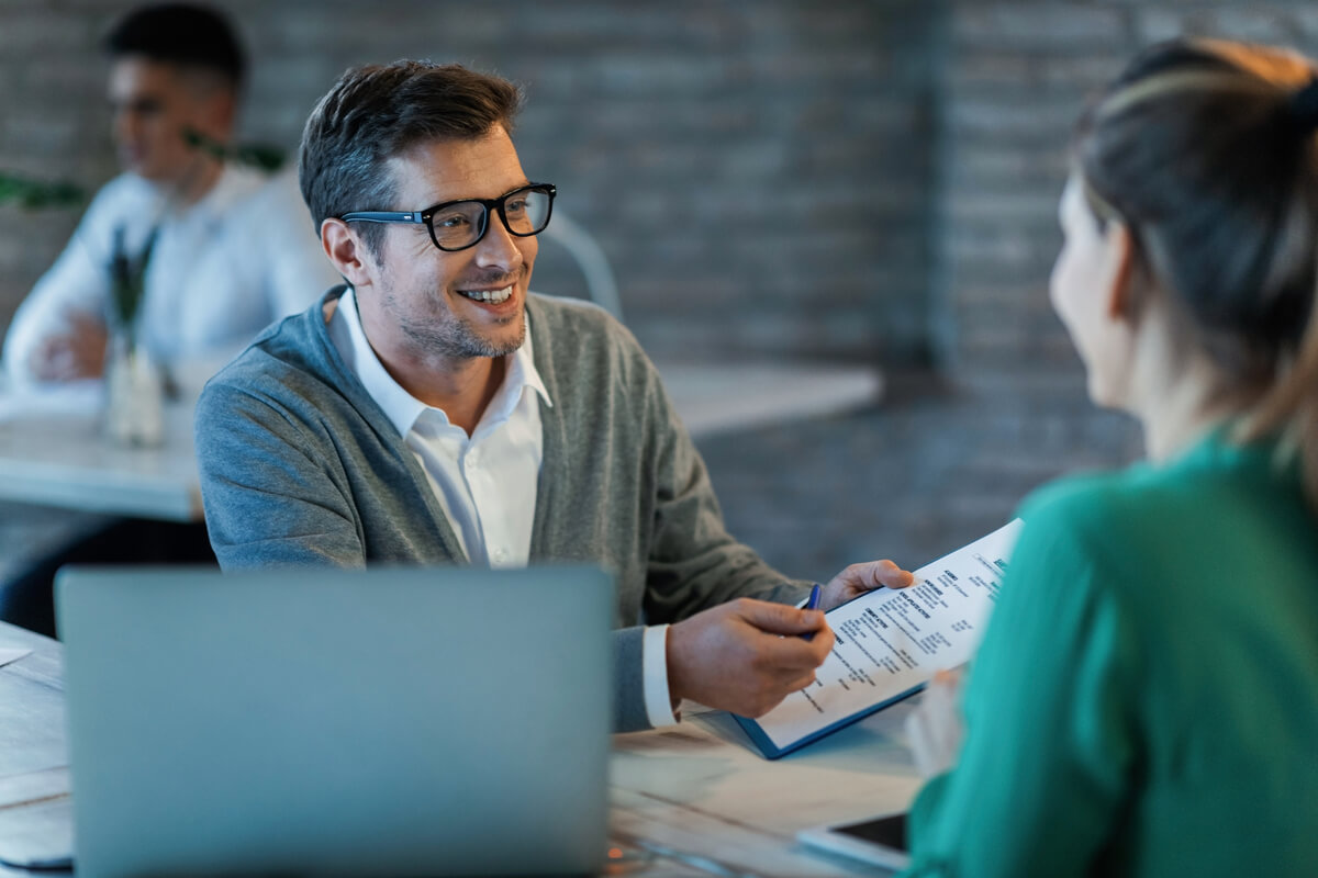 Un client signant des documents bancaires sur le bureau de son conseiller en agence.