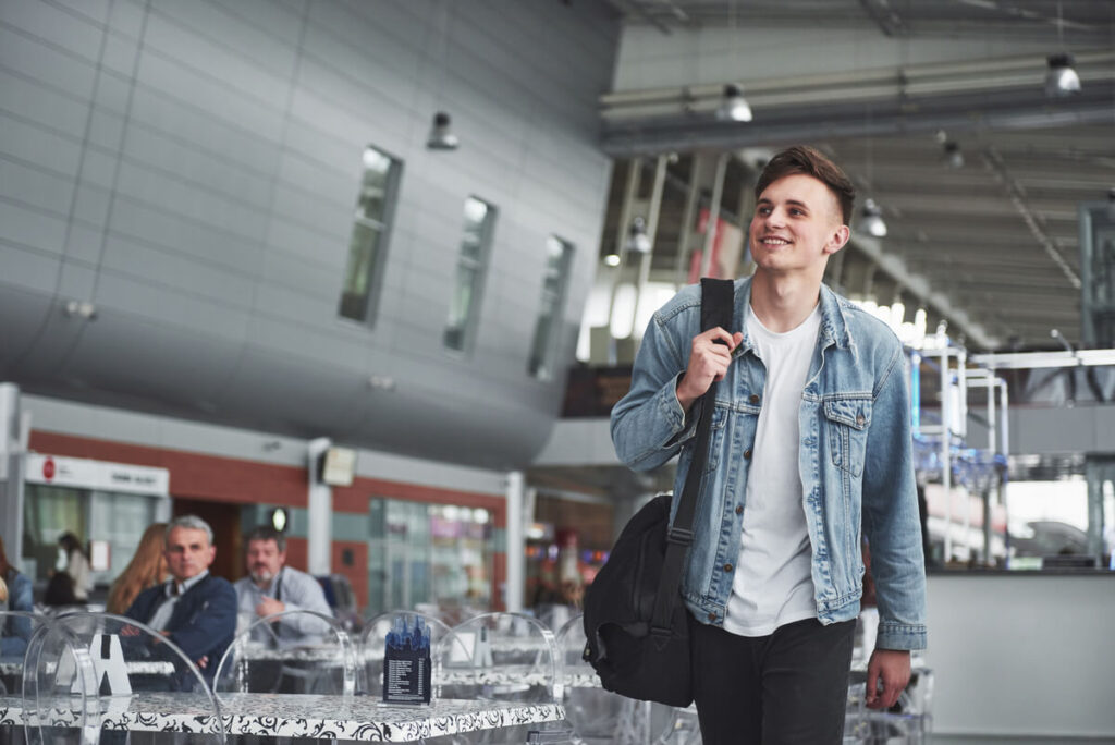Un voyageur tenant son passeport et son billet d'avion dans le terminal d'un aéroport.