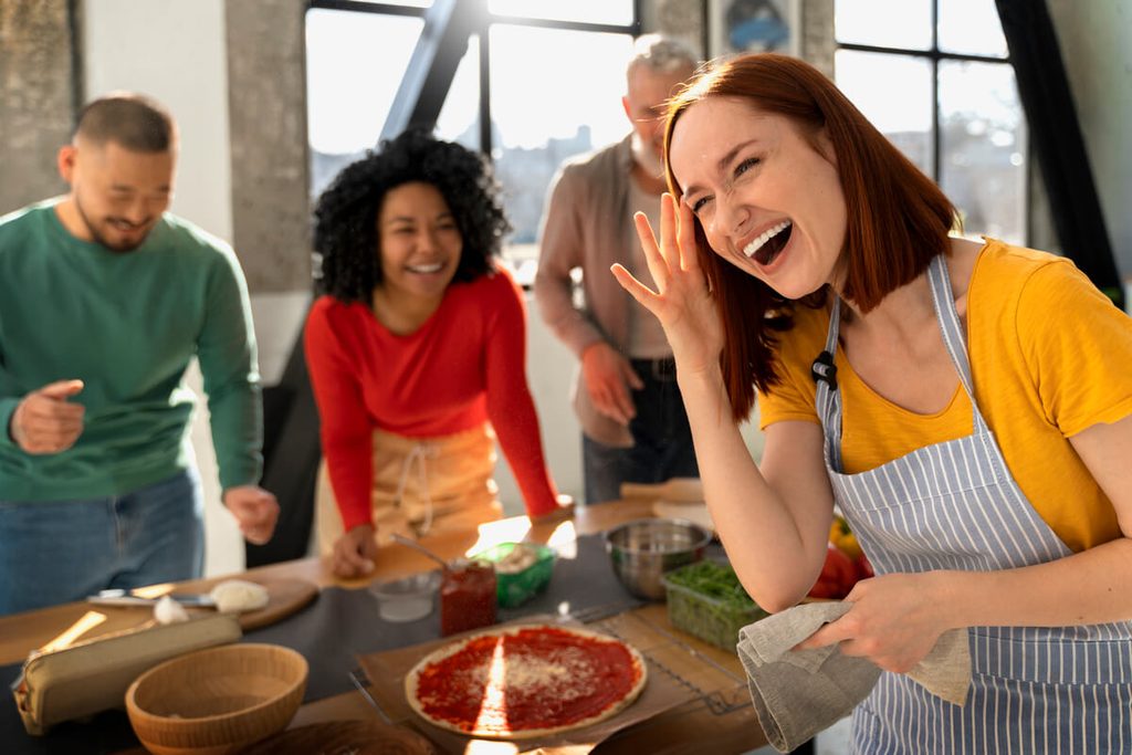 Équipe de travail souriante participant à un atelier culinaire de team building.