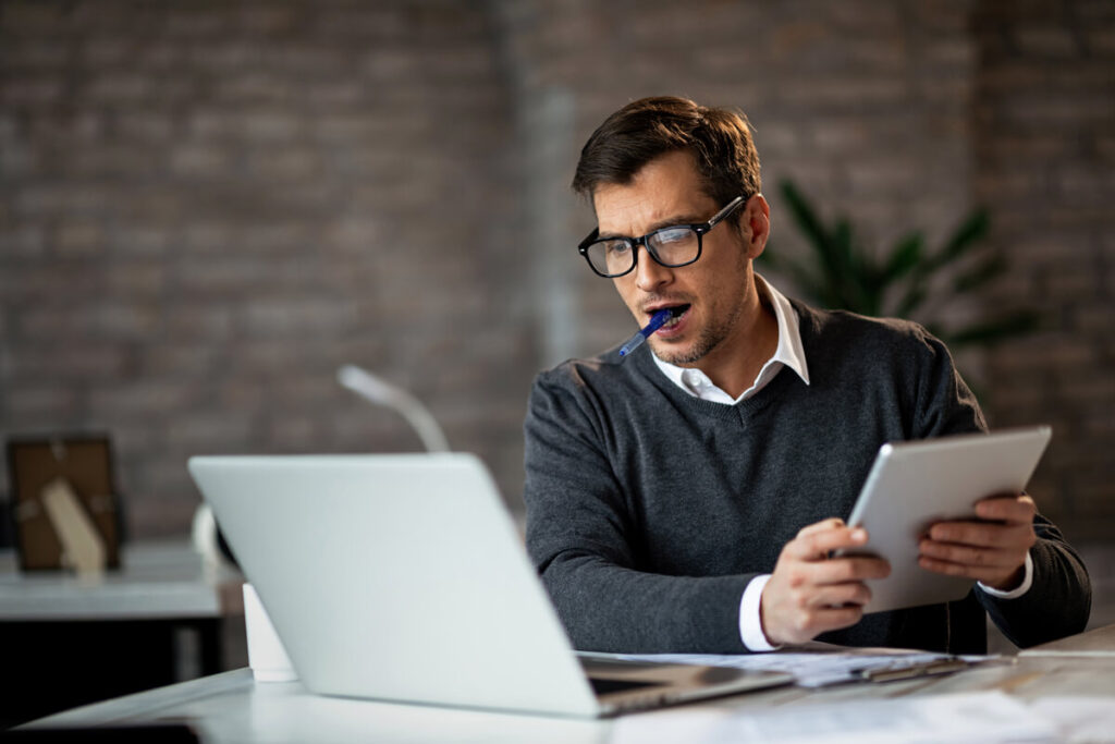 Un entrepreneur consultant la comptabilité de son entreprise depuis son ordinateur portable et son smartphone.