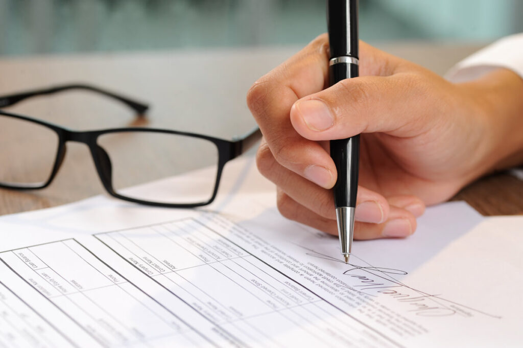 Personne apposant sa mention manuscrite et sa signature sur un acte de cautionnement.