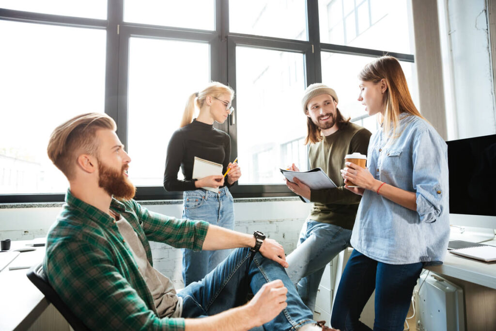 Quels avantages salariés proposer pour renforcer votre marque employeur ? 2 Équipe de collaborateurs souriants partageant une pause conviviale illustrant les avantages salariés et la culture d'entreprise.