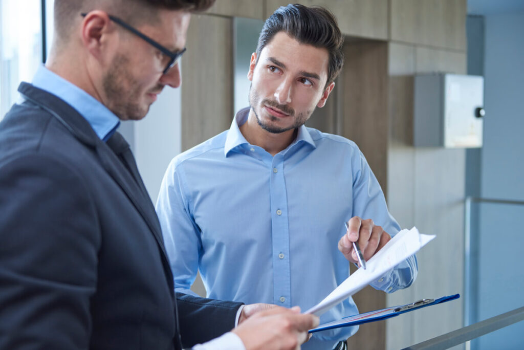 Dirigeant d'entreprise et conseiller bancaire examinant un tableau d'amortissement de crédit professionnel.