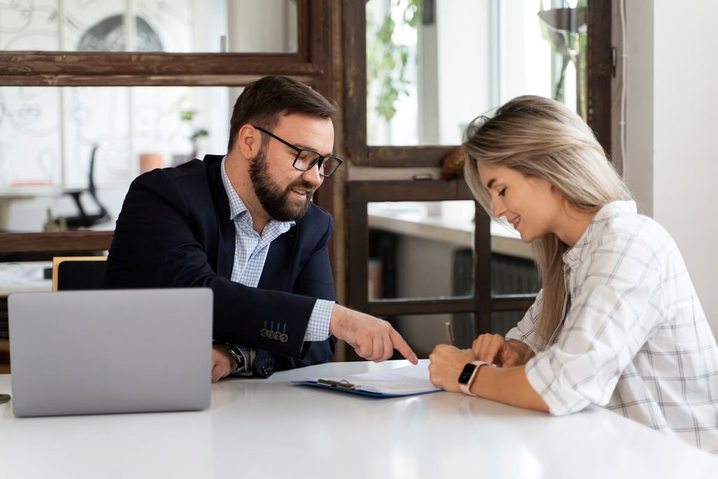Créer son entreprise : quel budget prévoir pour ses assurances au démarrage ? 3 Entrepreneur signant son premier contrat d'assurance responsabilité civile professionnelle en agence.