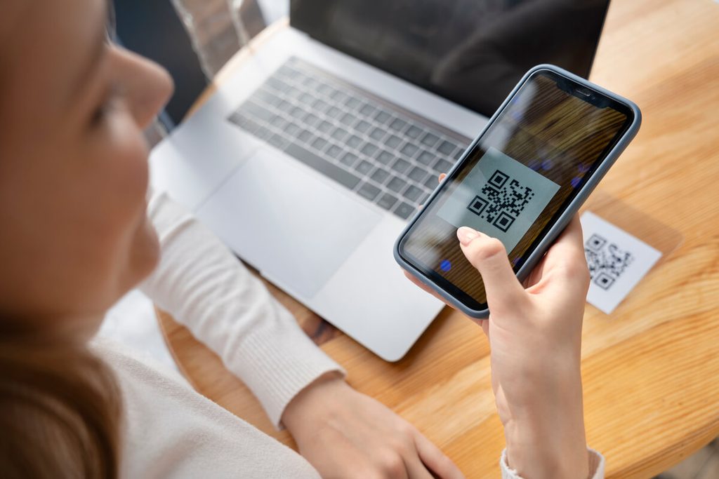 Smartphone scannant un QR code sur une carte de visite professionnelle pour enregistrer le contact.