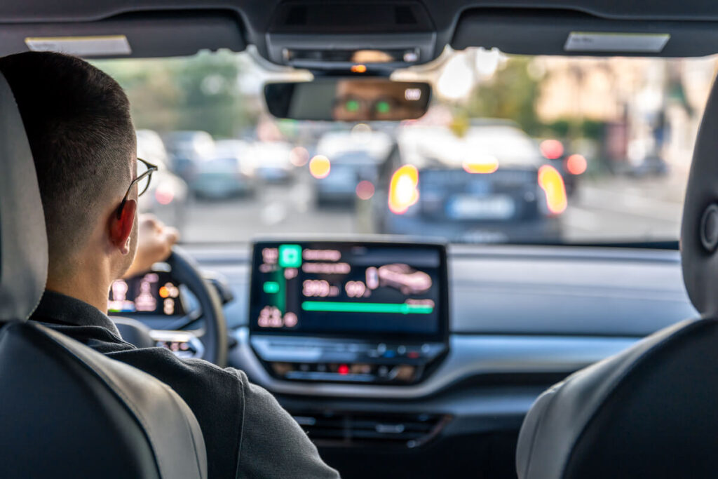 Chauffeur VTC consultant le montant d'une course sur l'application Uber fixée au tableau de bord.