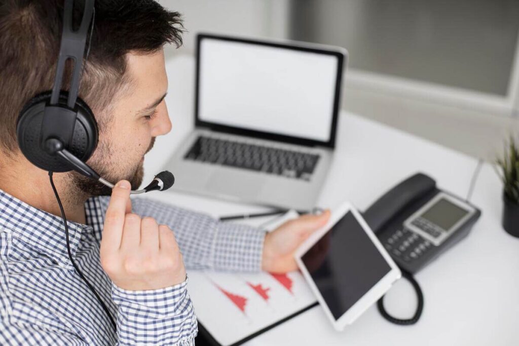 Téléconseiller avec micro-casque répondant à des appels clients sur un plateau d'assistance Teleperformance.