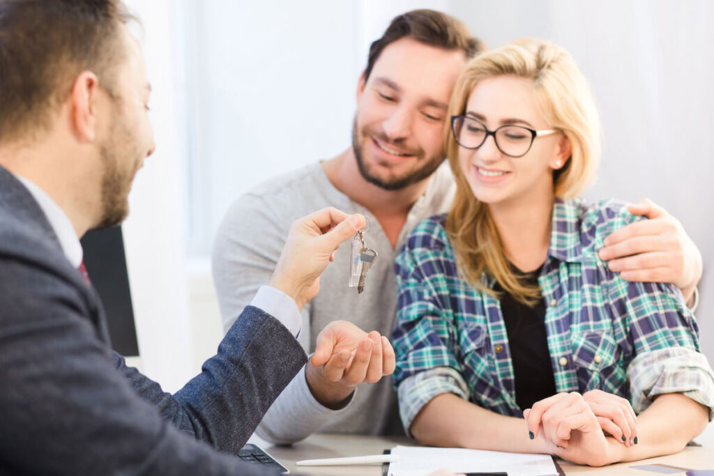 Signature d'un contrat d'achat immobilier avec remise des clés entre acheteur et propriétaire.